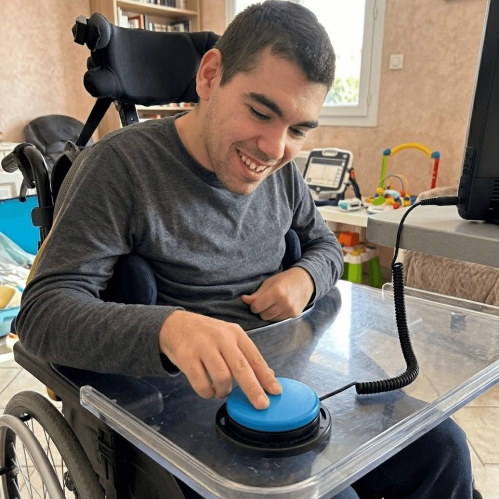 adulte avec paralysie cérébrale utilisant un contacteur bleu avec sa main