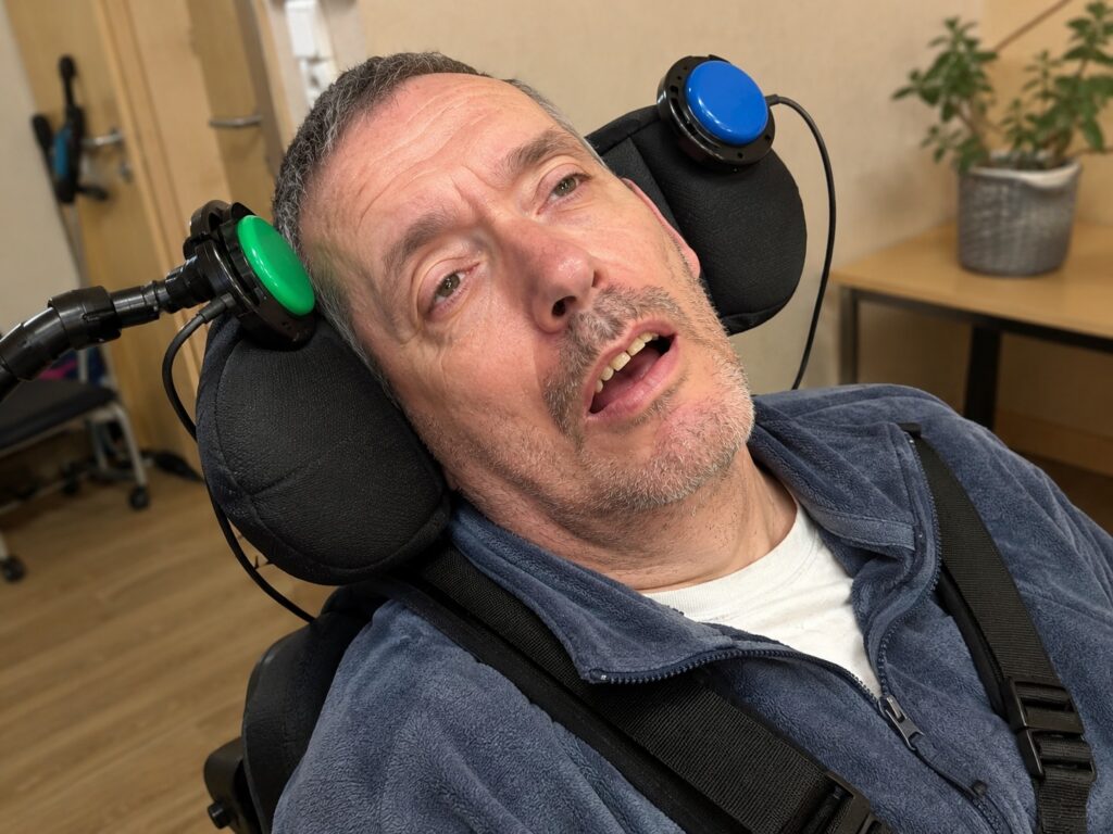 Comment choisir un contacteur adapté au handicap ? 2 Adulte utilisant deux contacteurs adaptés positionnés sur la têtière de son fauteuil roulant