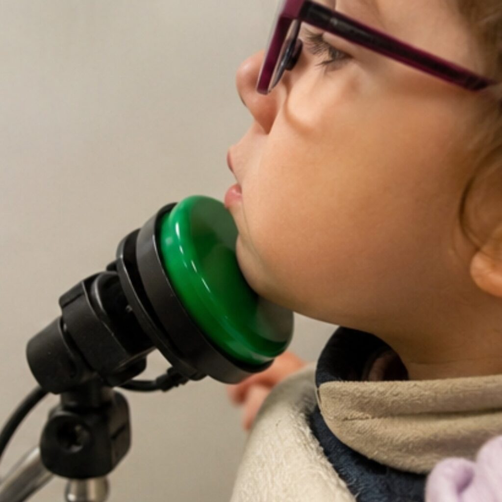Comment choisir un contacteur adapté au handicap ? 5 Enfant utilisant un contacteur avec le menton pour accéder à une activité adaptée