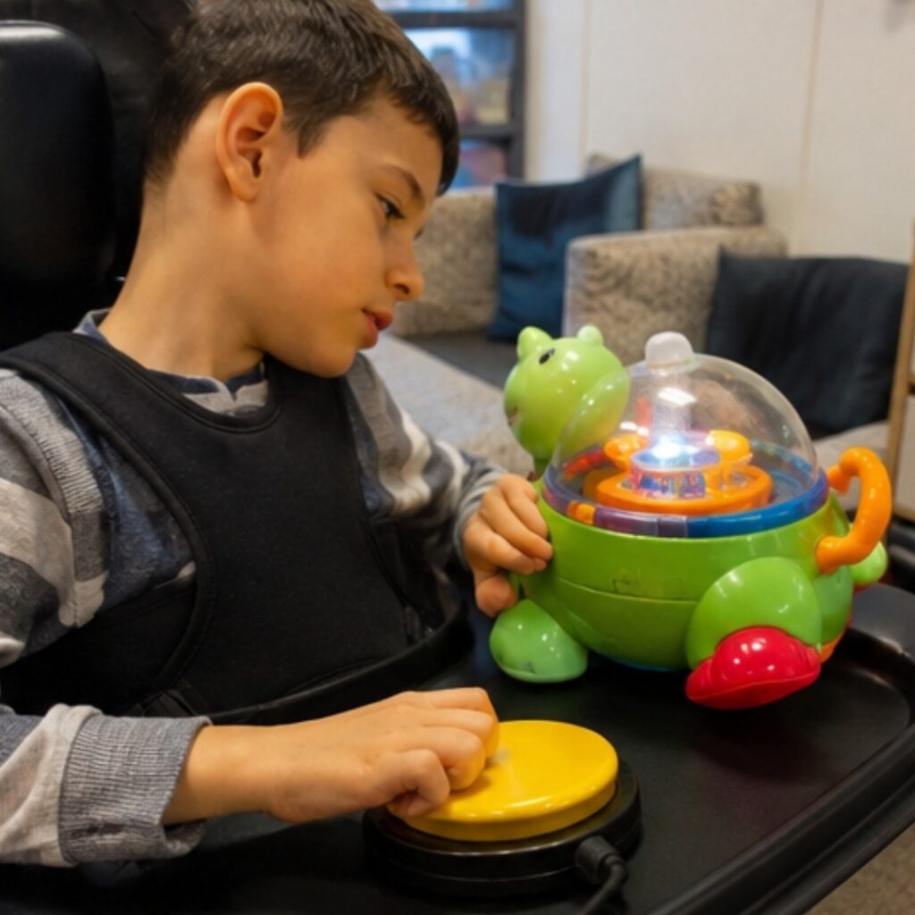 Comment choisir un contacteur adapté au handicap ? 3 Enfant utilisant un contacteur adapté pour déclencher un jouet accessible